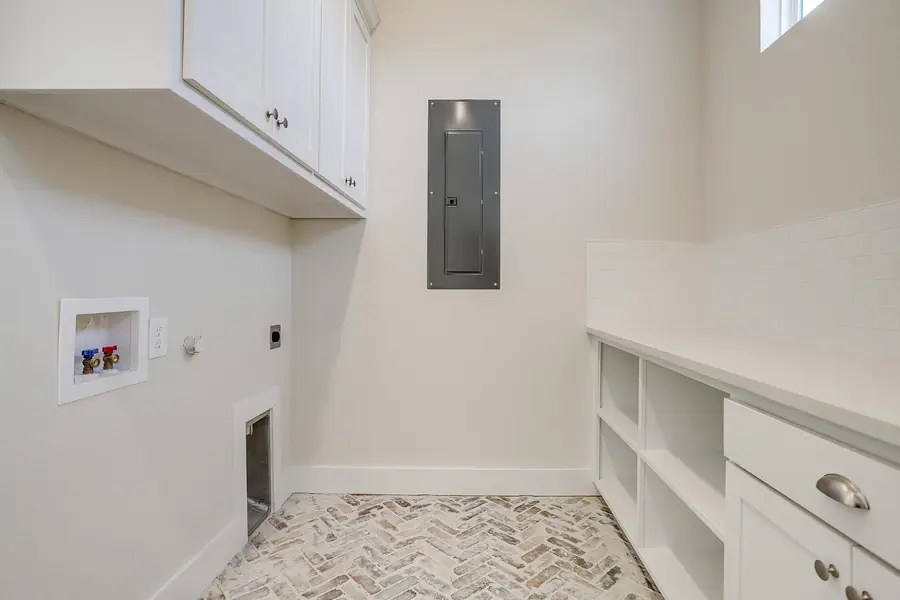 Laundry room with herringbone brick floors and white cabinetry