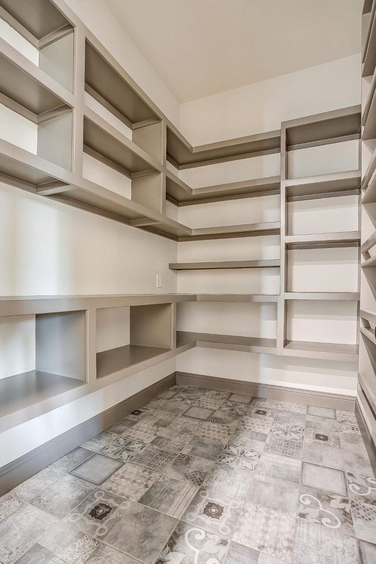 Walk-in pantry with gray shelving and patterned floor tile