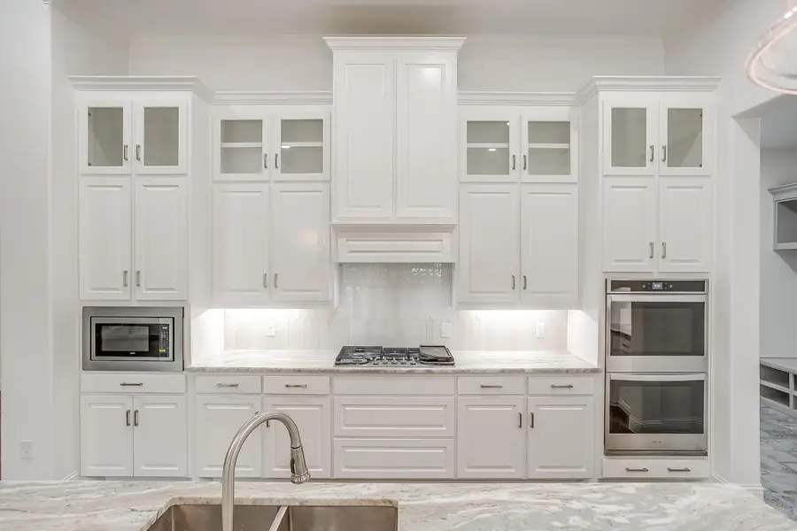Symmetrical view of white kitchen cabinetry and range wall