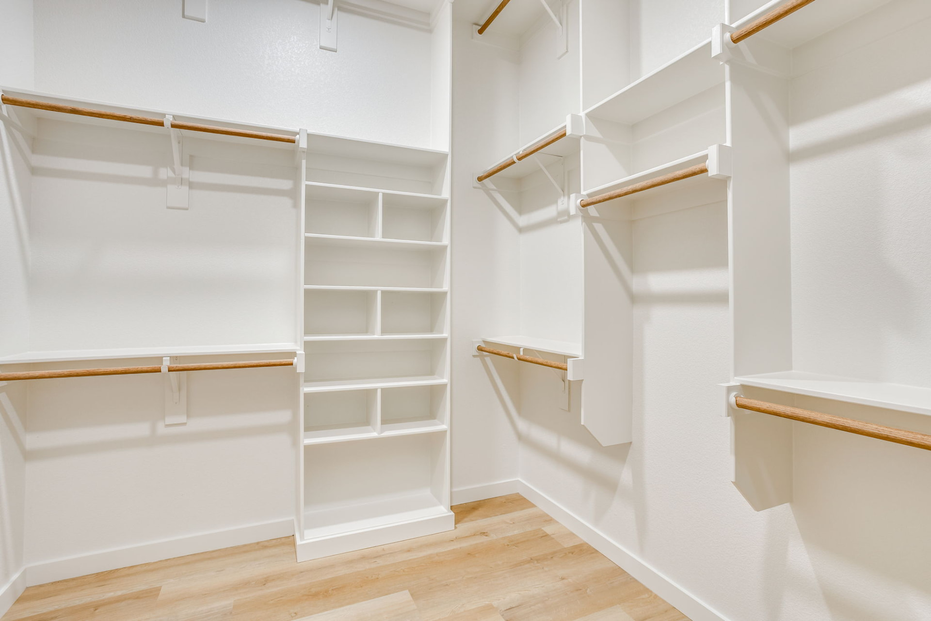 Walk-in primary closet with custom white built-ins