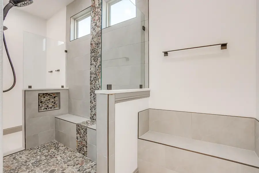 Walk-in shower with pebble floor and stone tile walls