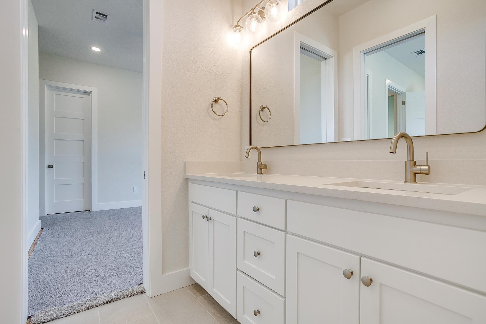 Bright guest bathroom with two sinks and neutral tile