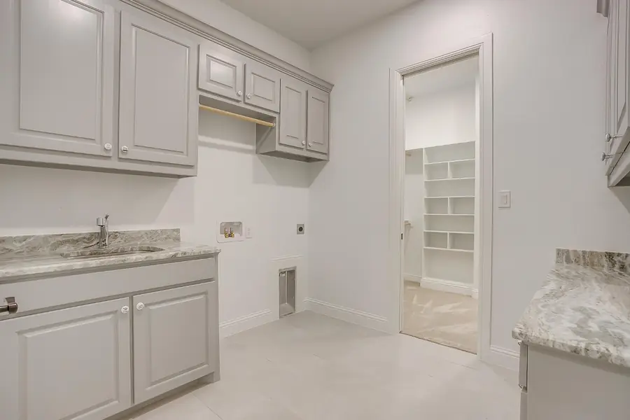 Laundry room with gray cabinetry, stone counters, and a sink