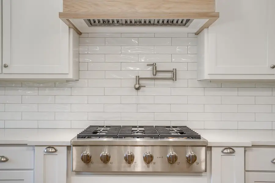 Professional gas range with subway tile backsplash and a pot filler