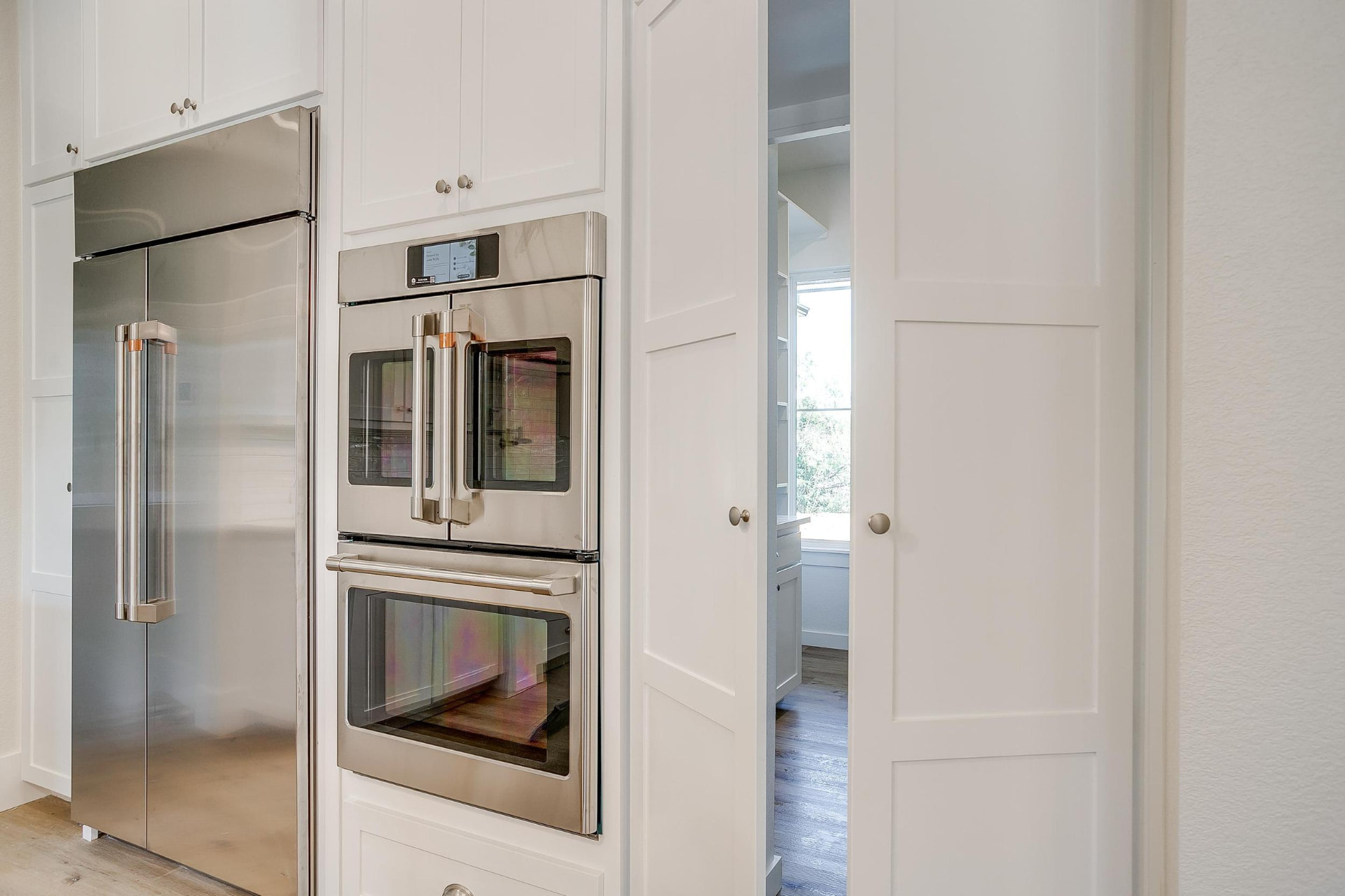 White pantry doors beside the built-in ovens