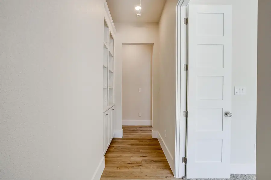 Hallway with white shaker doors and wood flooring