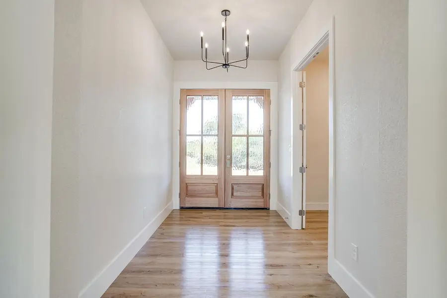 Entry foyer seen through the wood front door with a black chandelier
