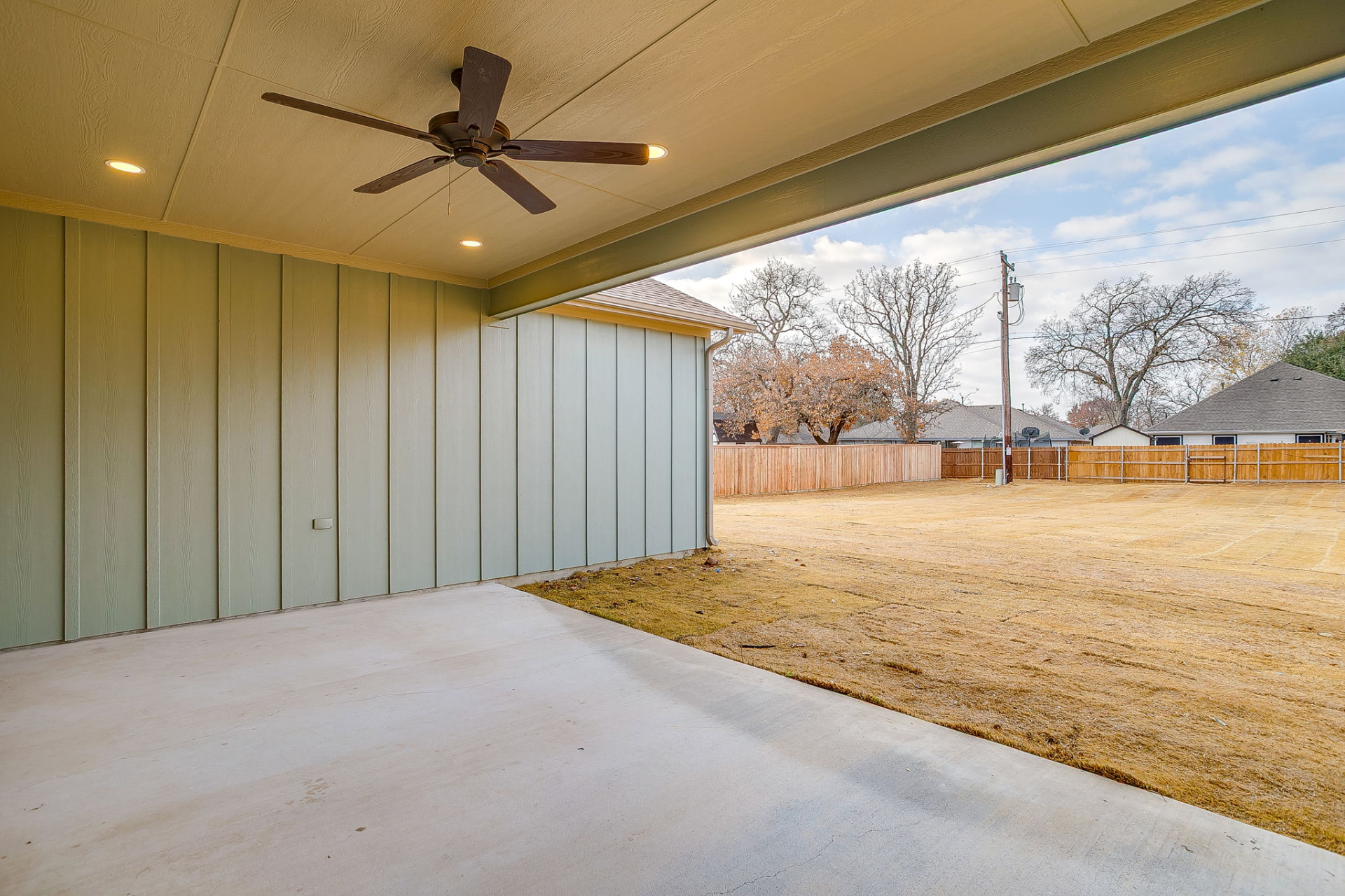 Covered rear patio with ceiling fan overlooking the fenced backyard