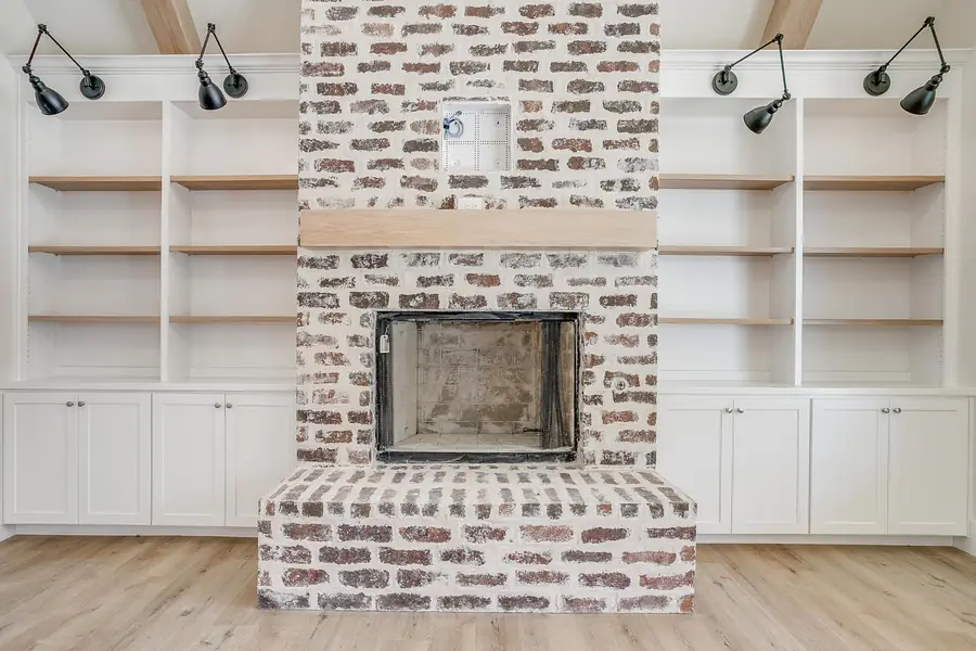 White brick fireplace with a light wood mantel and black sconces