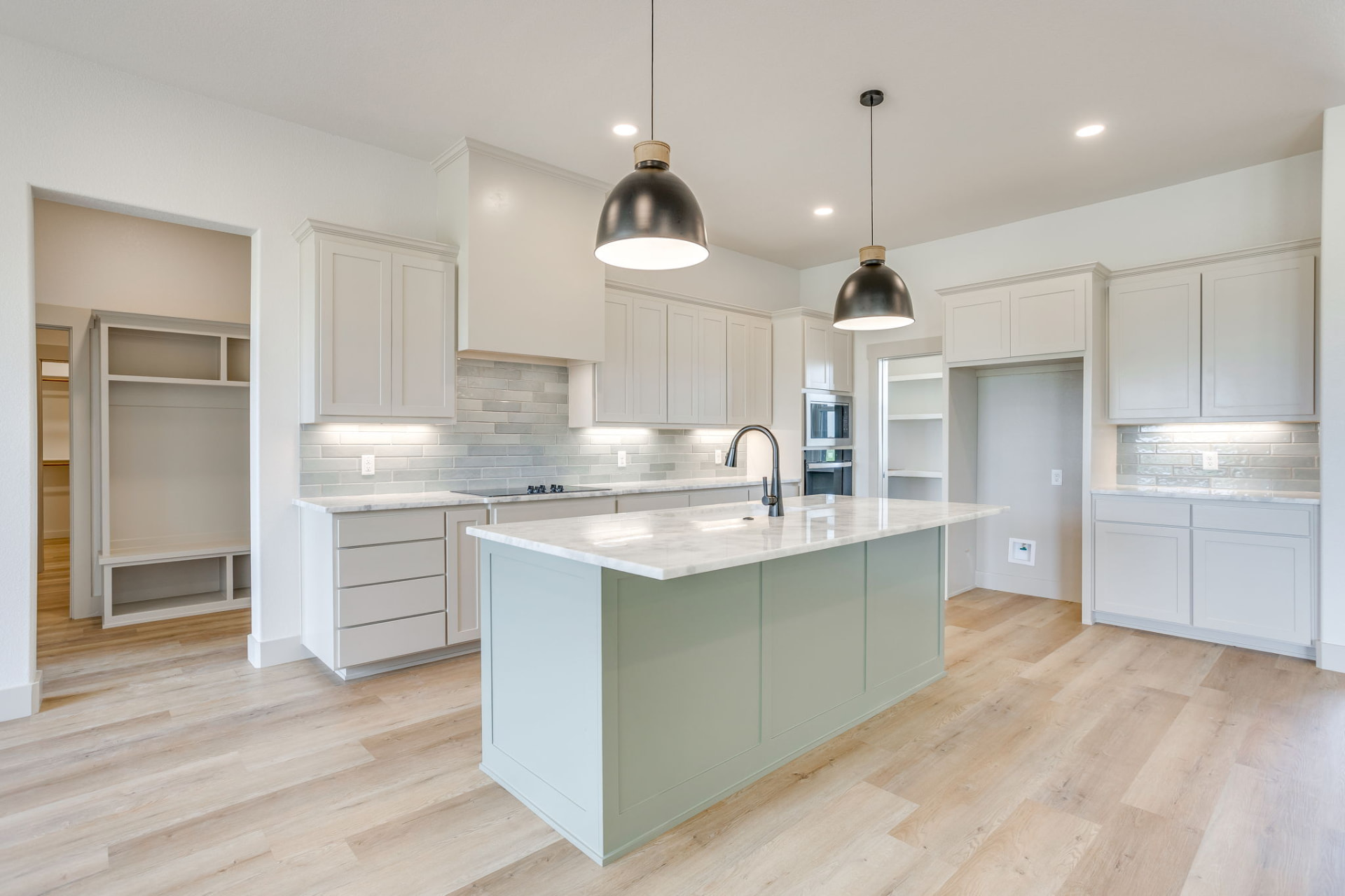 White kitchen cabinetry with sage island and black hardware