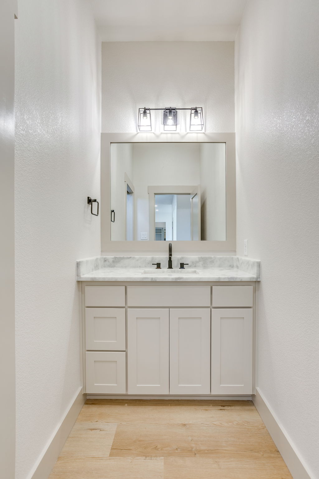 Powder bath with a marble-topped vanity and framed mirror