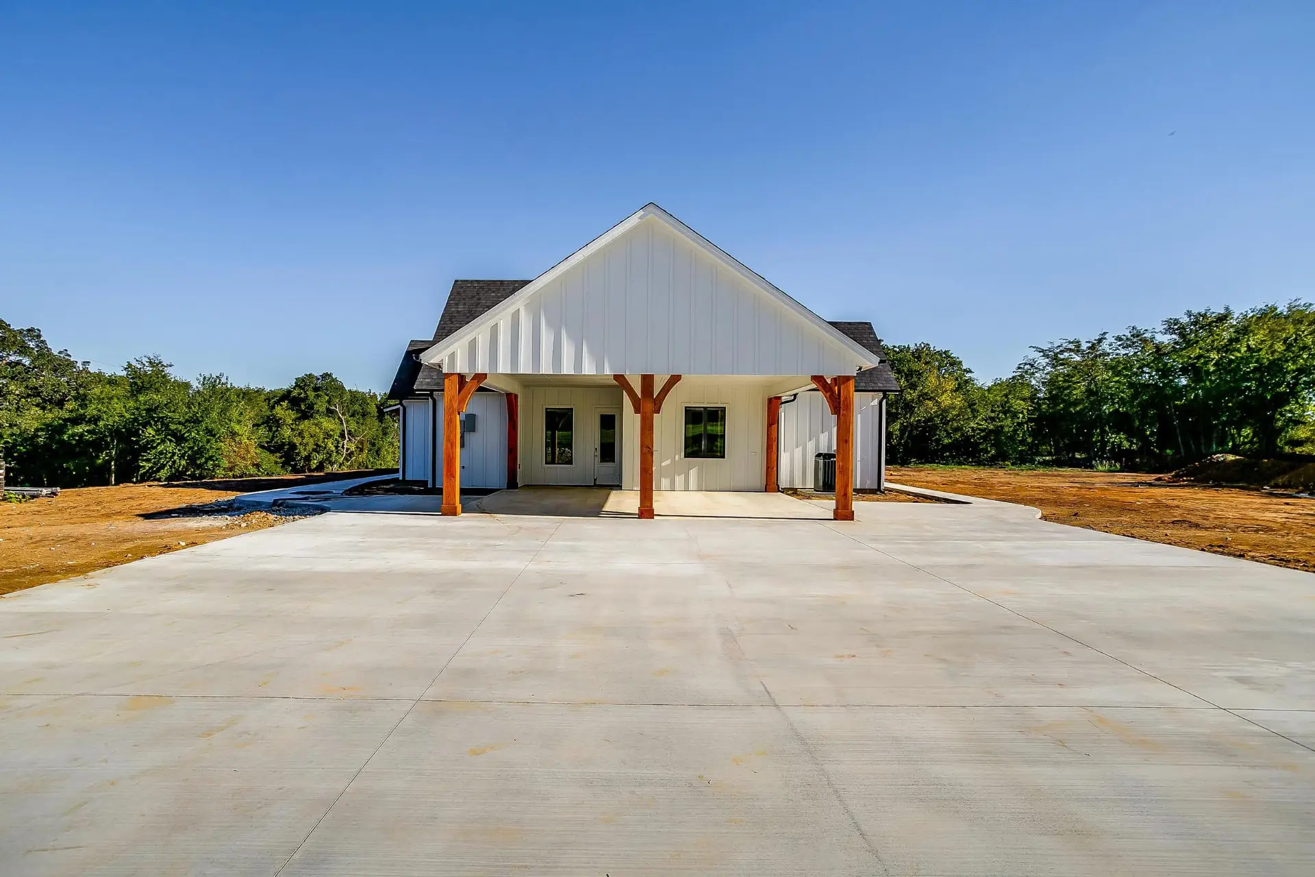 Modern white farmhouse exterior under a clear Texas sky
