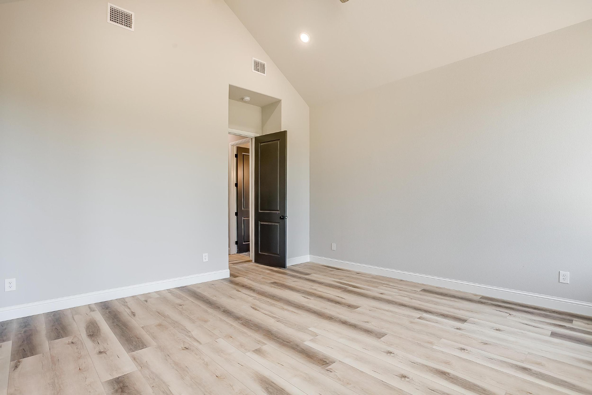 Bedroom with high ceilings and dark gray door