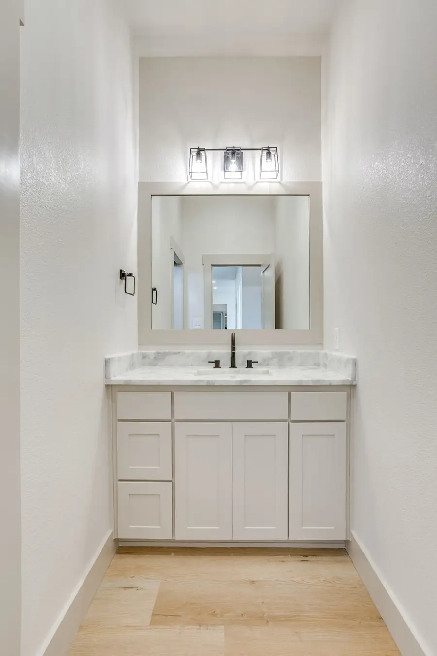 Powder bath with a marble-topped vanity and framed mirror