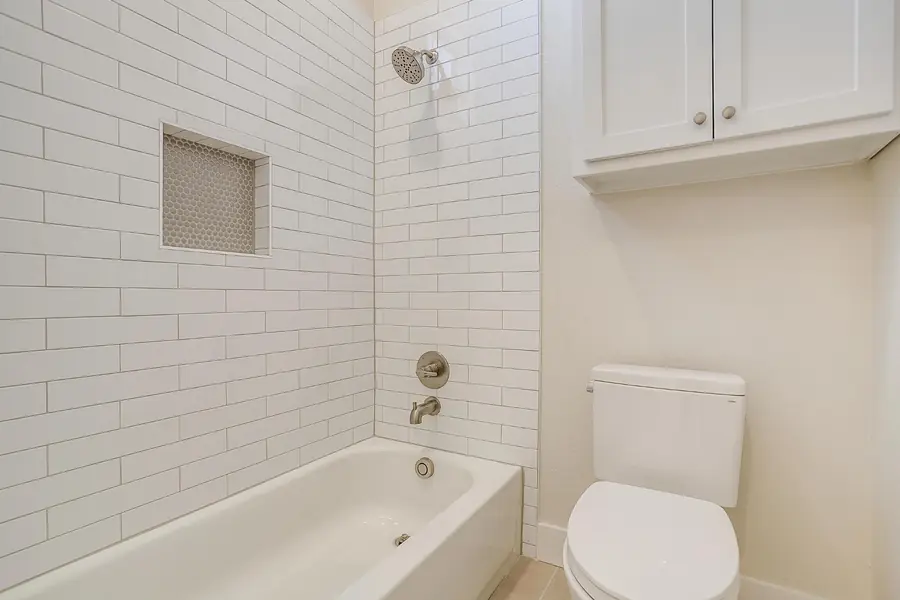 Shower-tub combo with vertical white subway tile and a niche