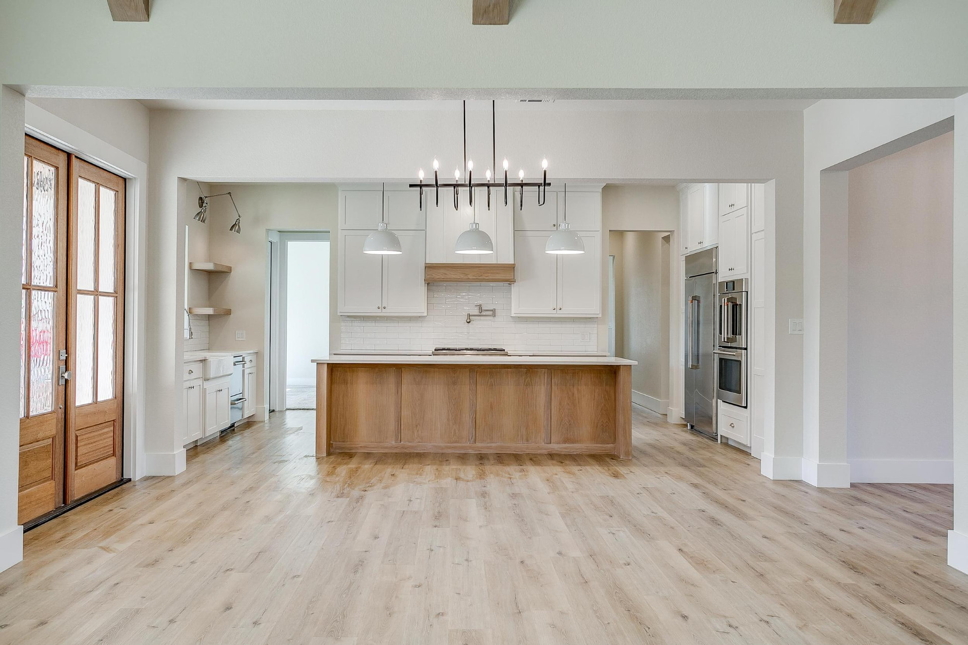 Kitchen with a wood island, white cabinetry, and a black linear chandelier