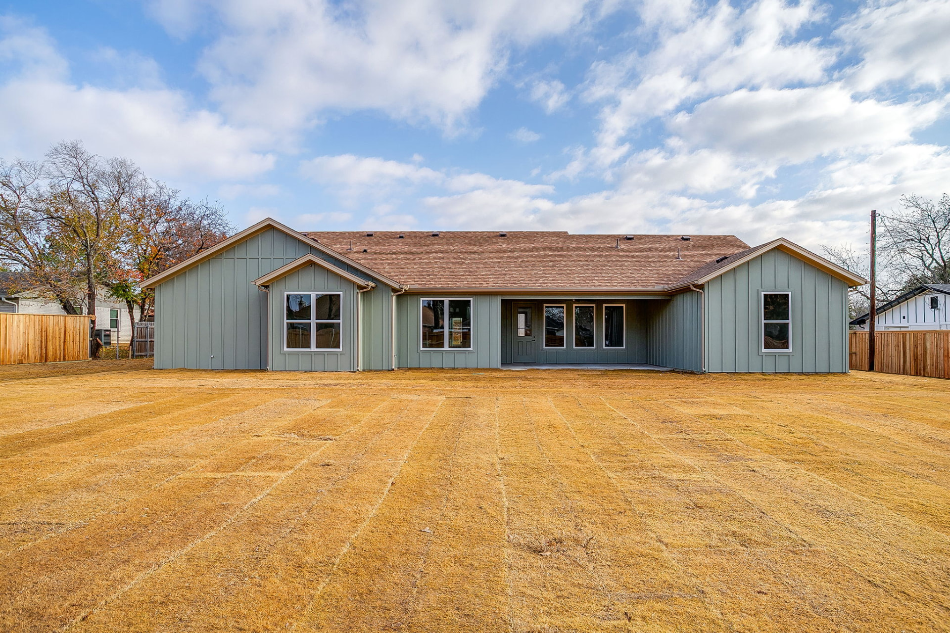 Straight-on rear view of the Granbury custom home across the fenced backyard