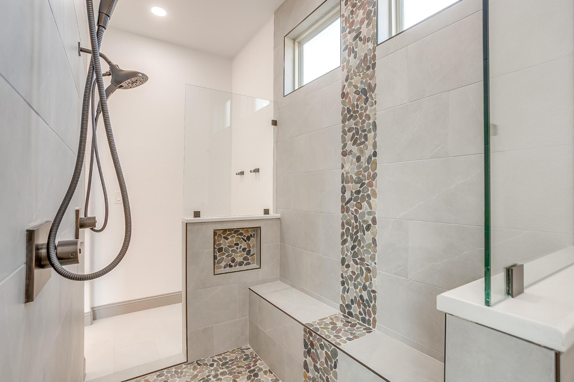 Walk-in shower with glass panel, bench seat, and tiled niche