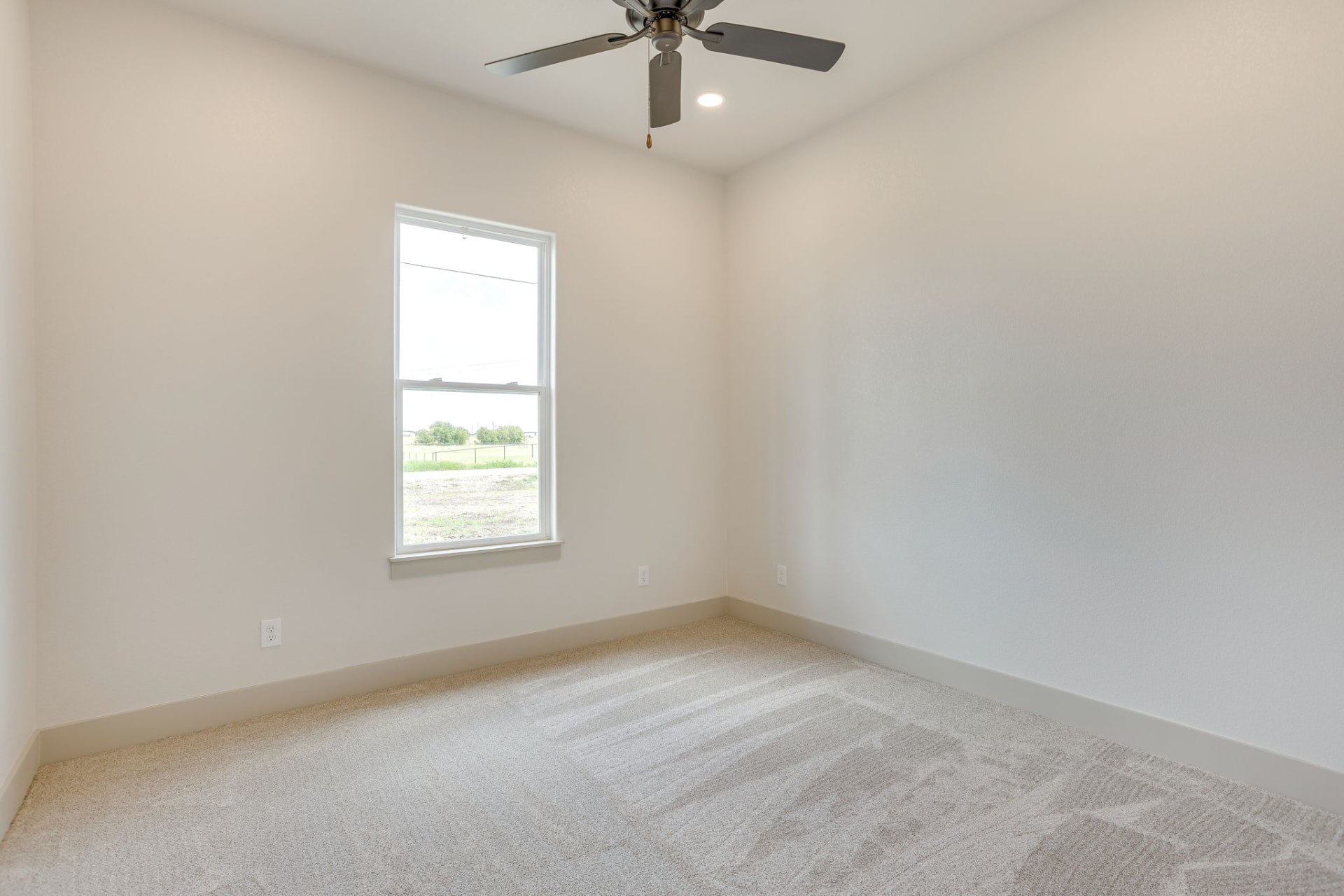 Secondary bedroom with a tall window and neutral finishes