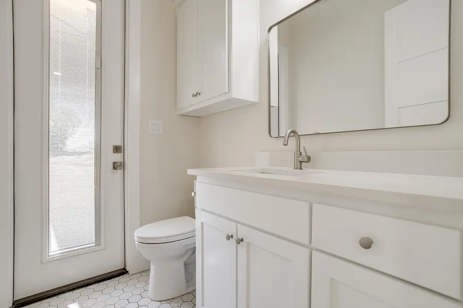 Bath vanity with white cabinets and a gold-framed mirror