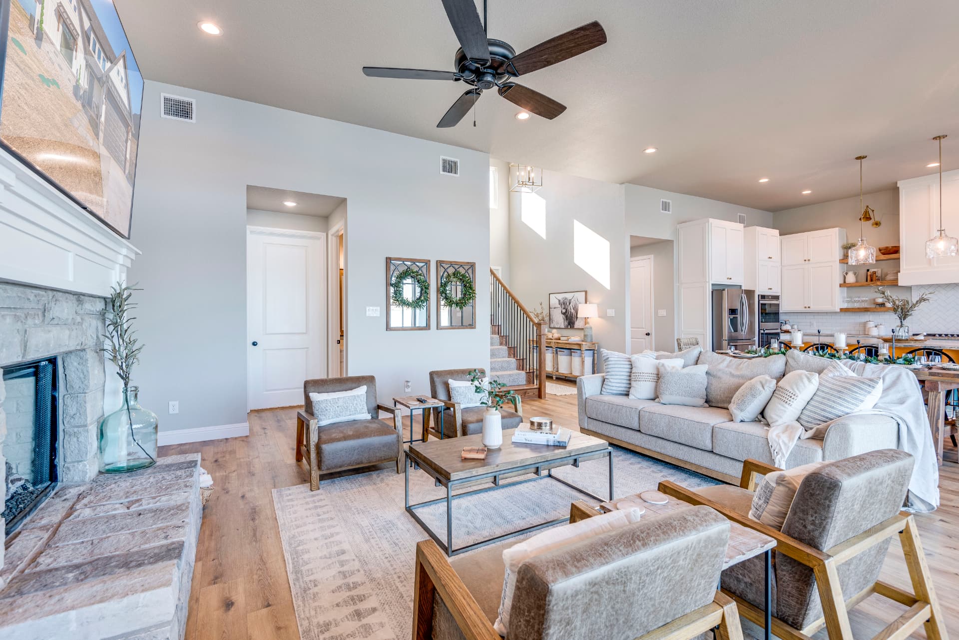 Open living area with gray armchairs, sofa, and kitchen beyond