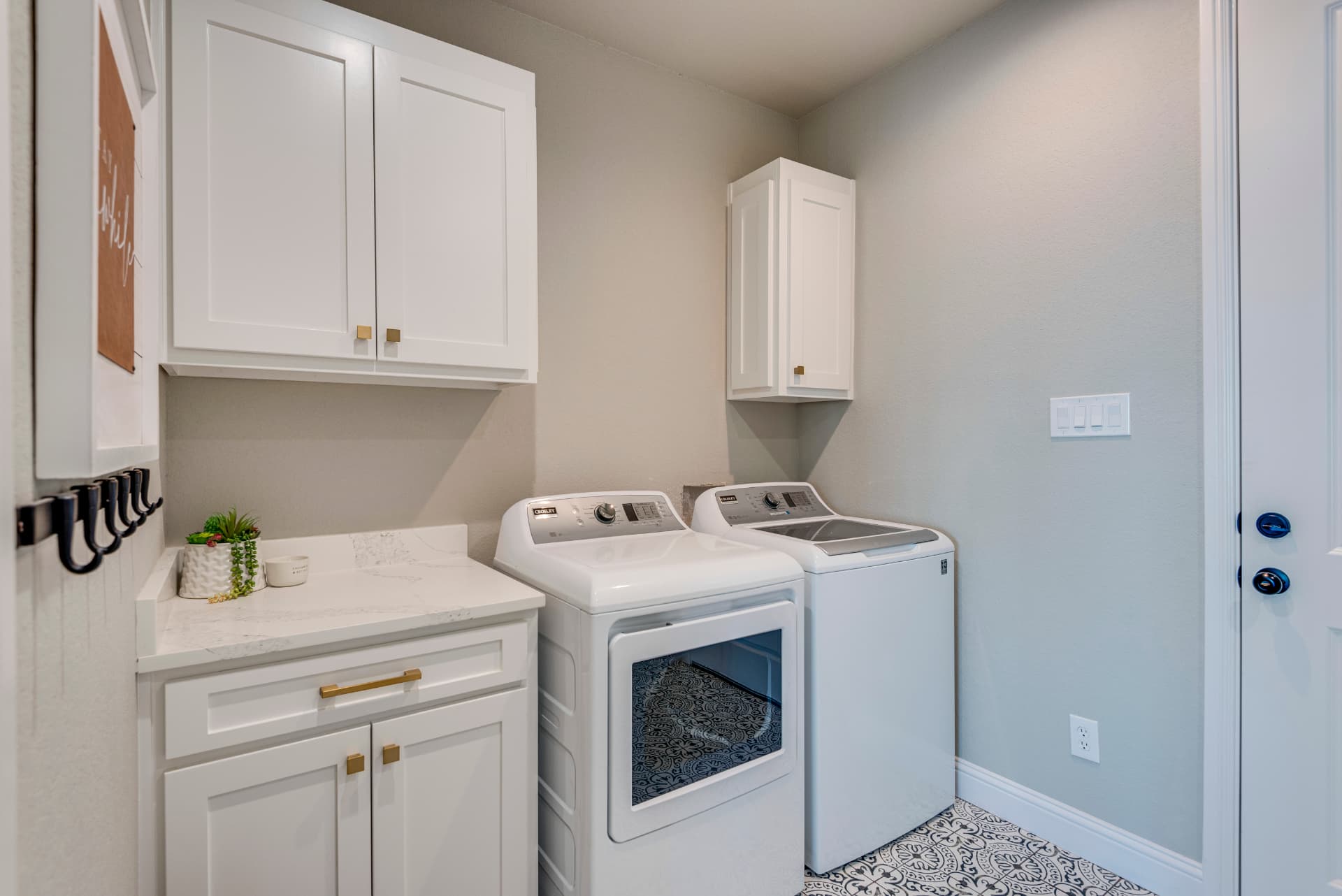 Laundry room with white cabinetry and patterned floor tile
