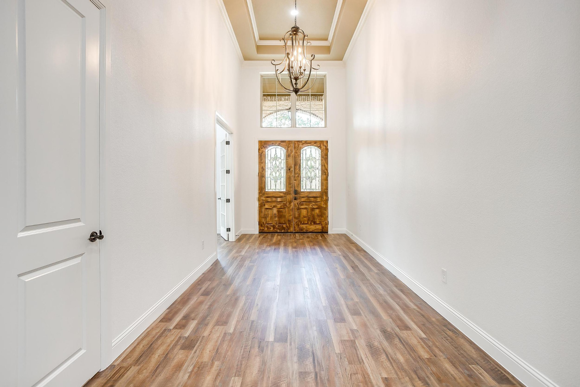 Two-story entry foyer with dark wood flooring and a view into the living room