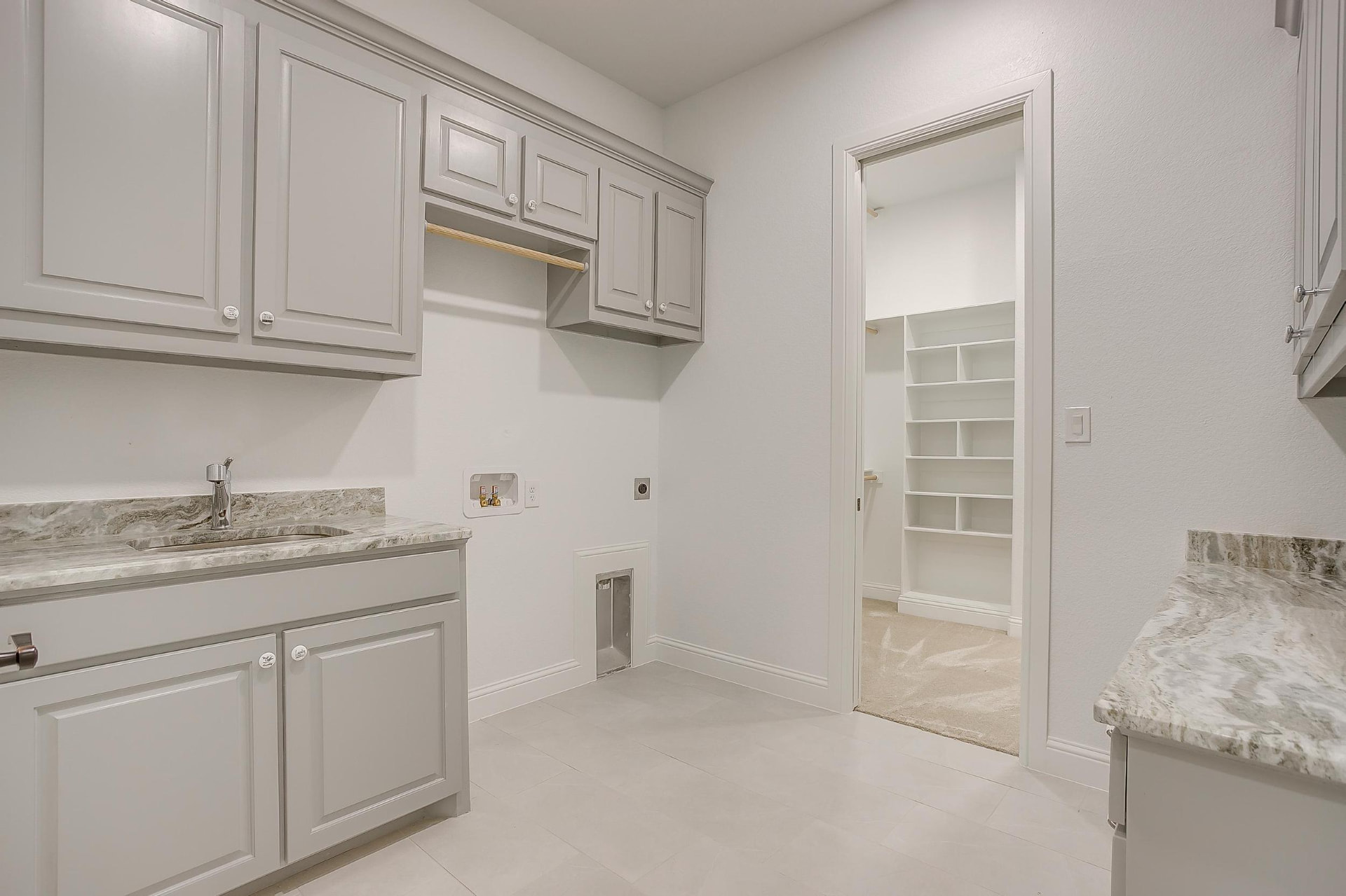 Laundry room with gray cabinetry, stone counters, and a sink