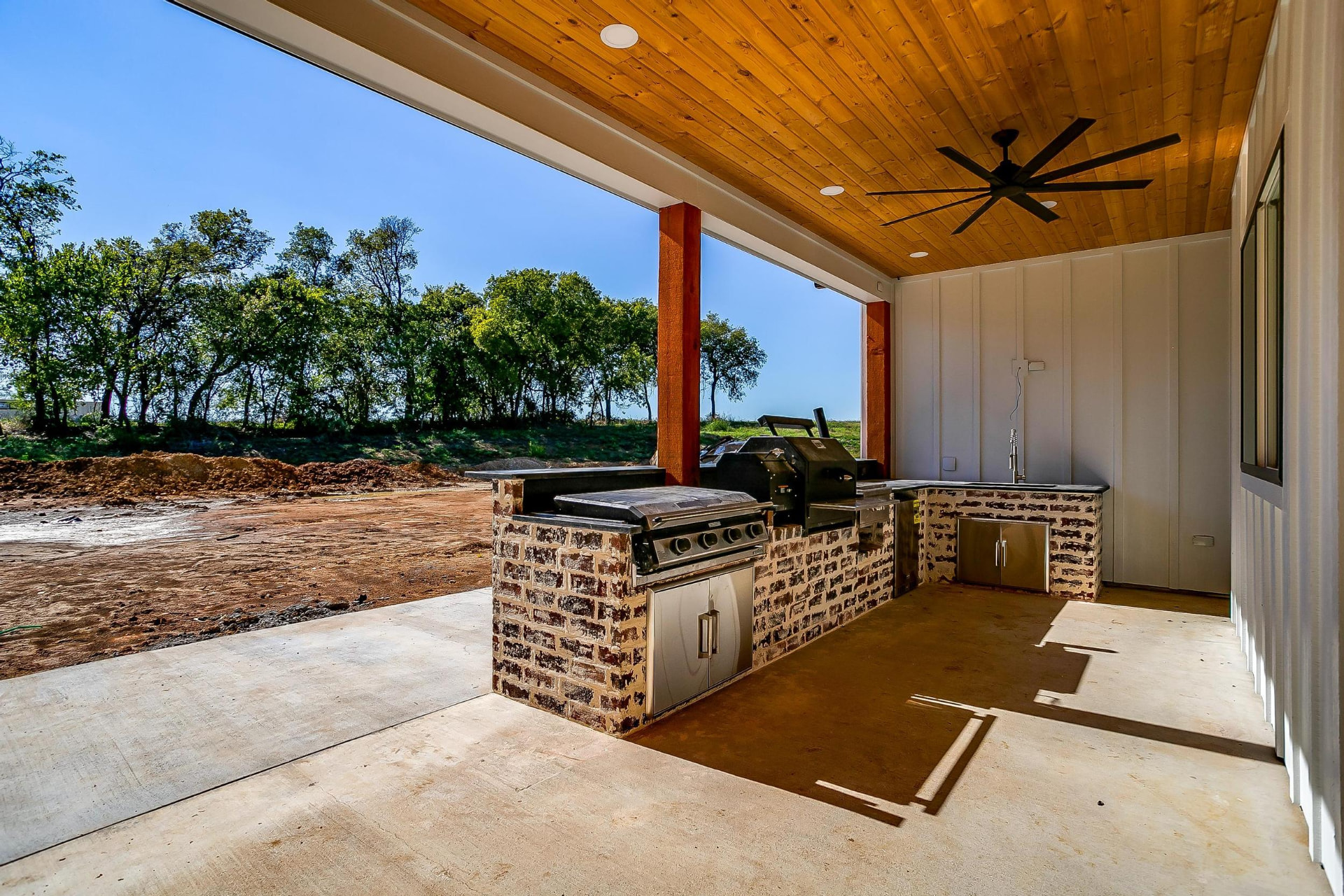 Outdoor kitchen with a built-in grill, smoker, and brick surround