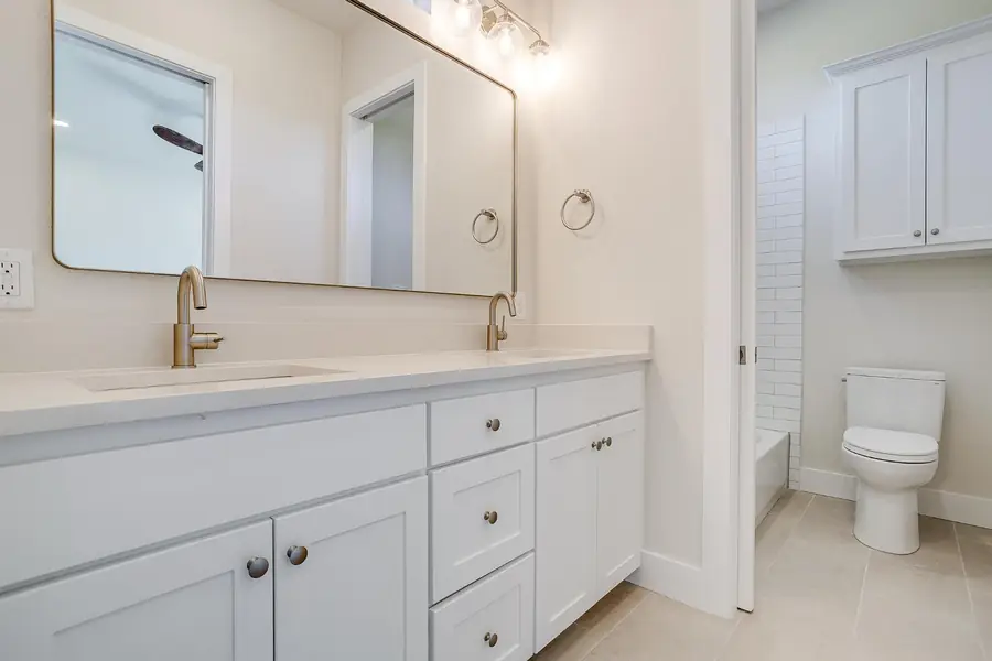 Guest bathroom with a white double vanity and gold faucets