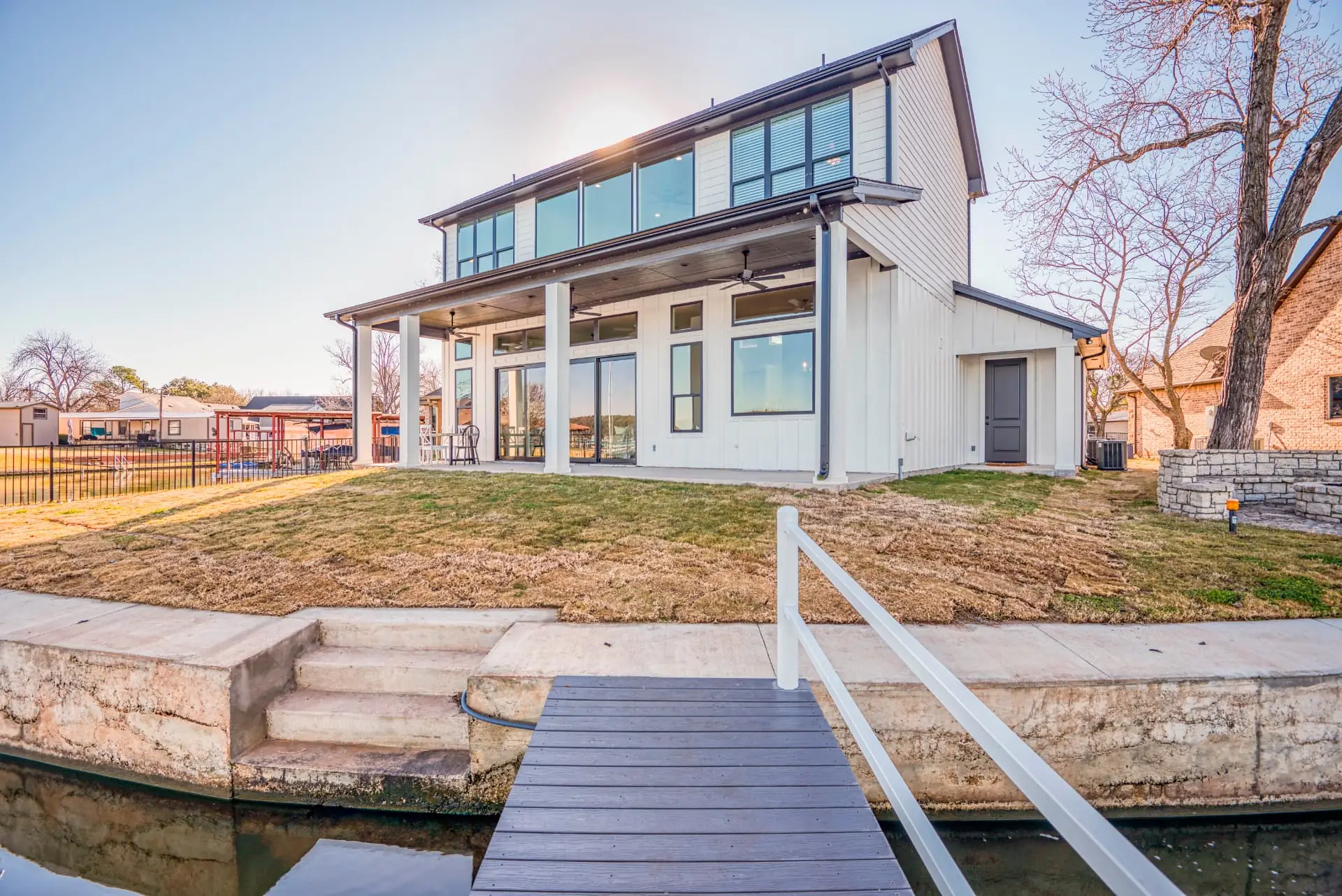 Rear exterior of a white lakefront custom home with black-trimmed windows