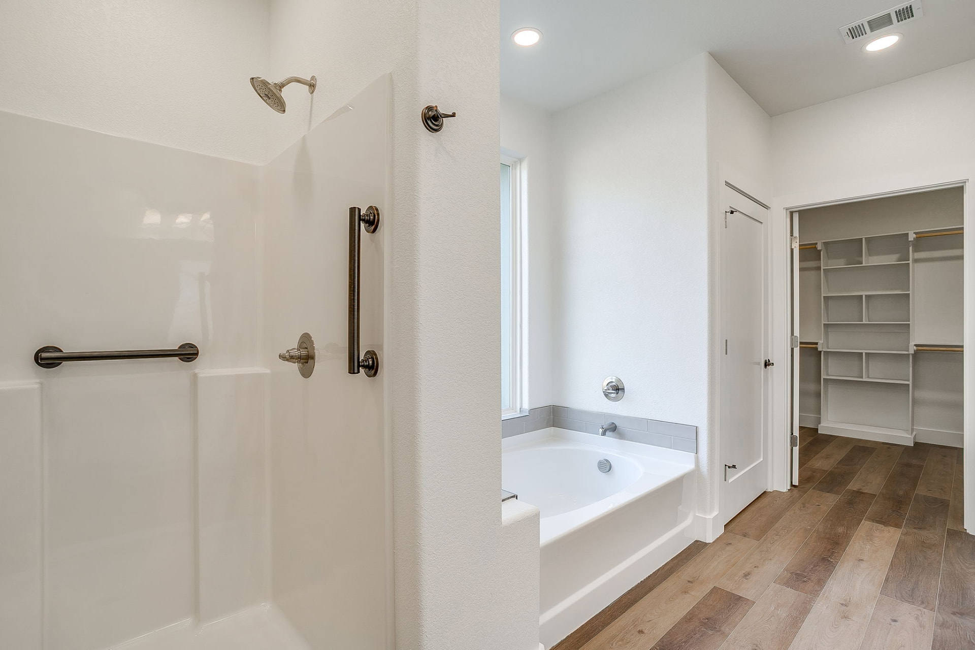 Walk-in shower, soaking tub, and closet entry in the primary bath