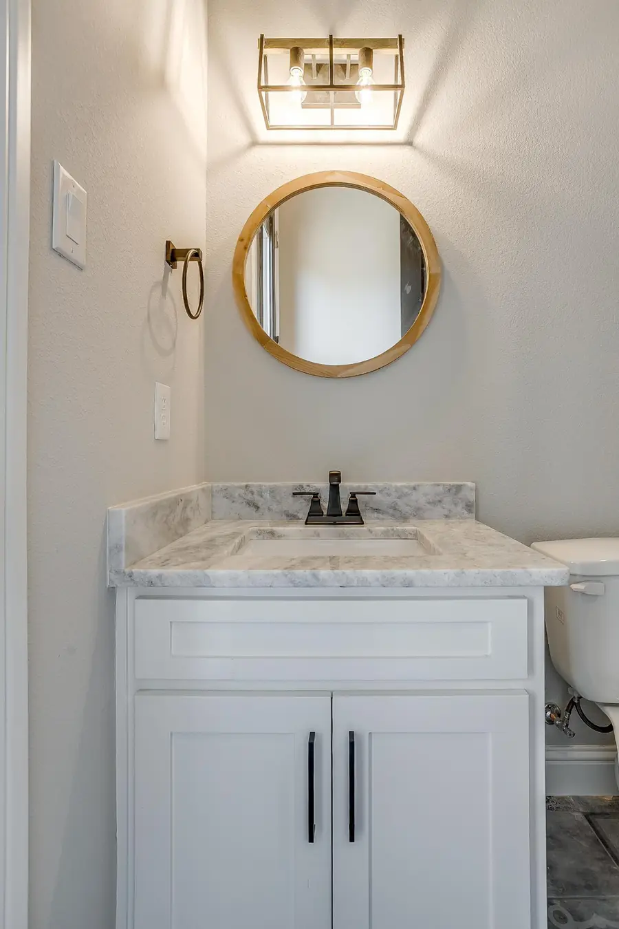 Powder room vanity with round wood-framed mirror