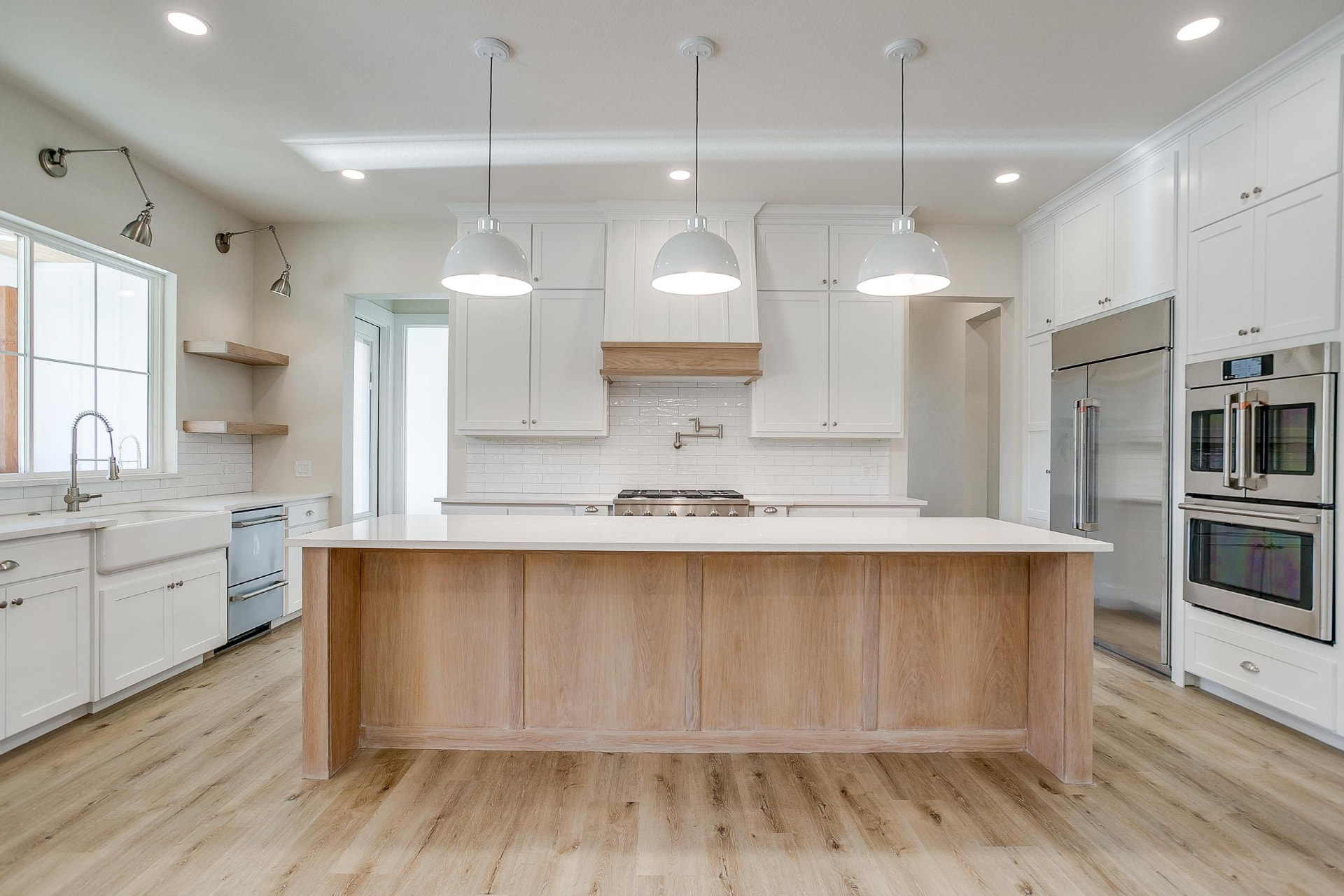 Kitchen with a large marble-topped wood island and white cabinetry