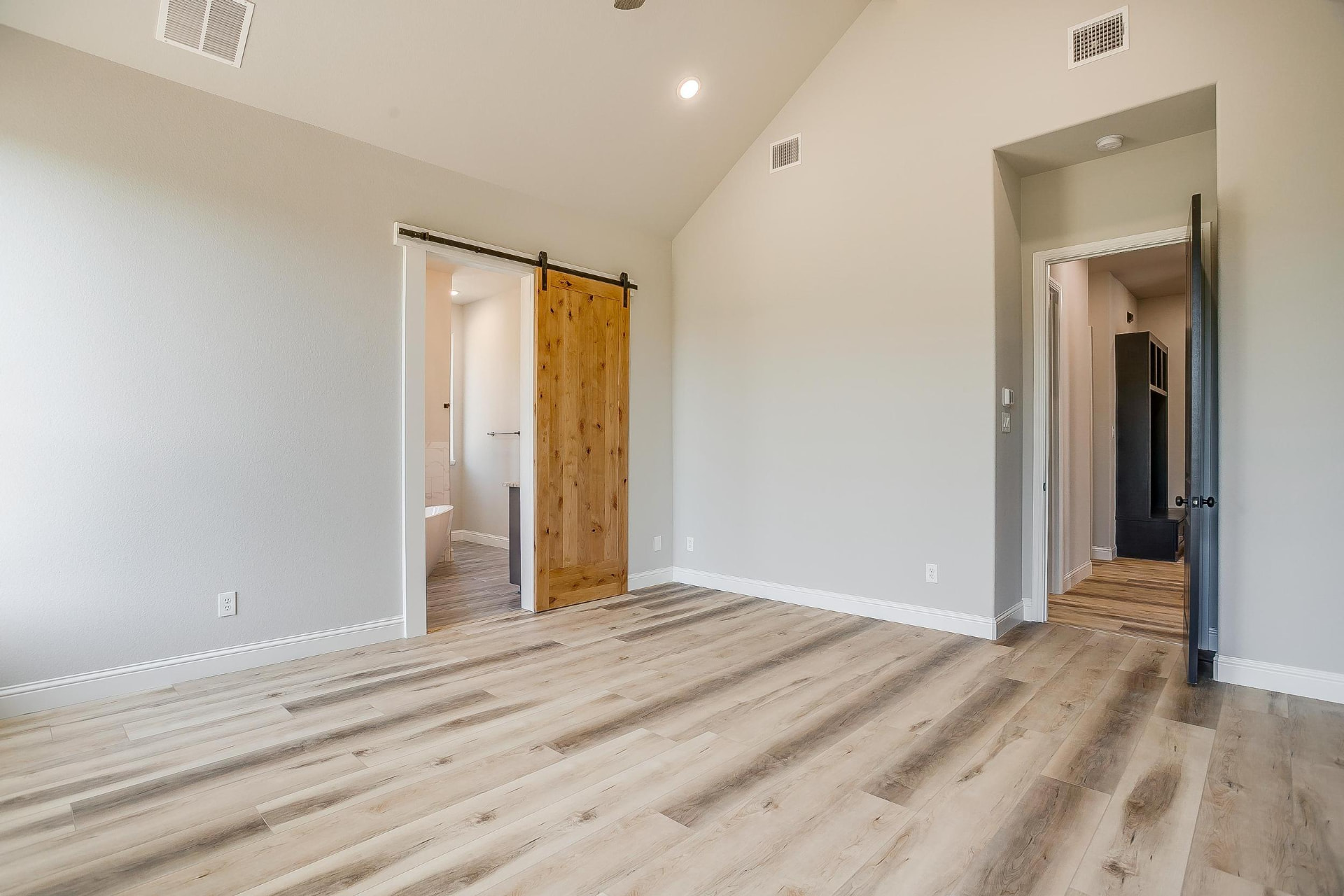Primary bedroom with barn door and gabled ceiling