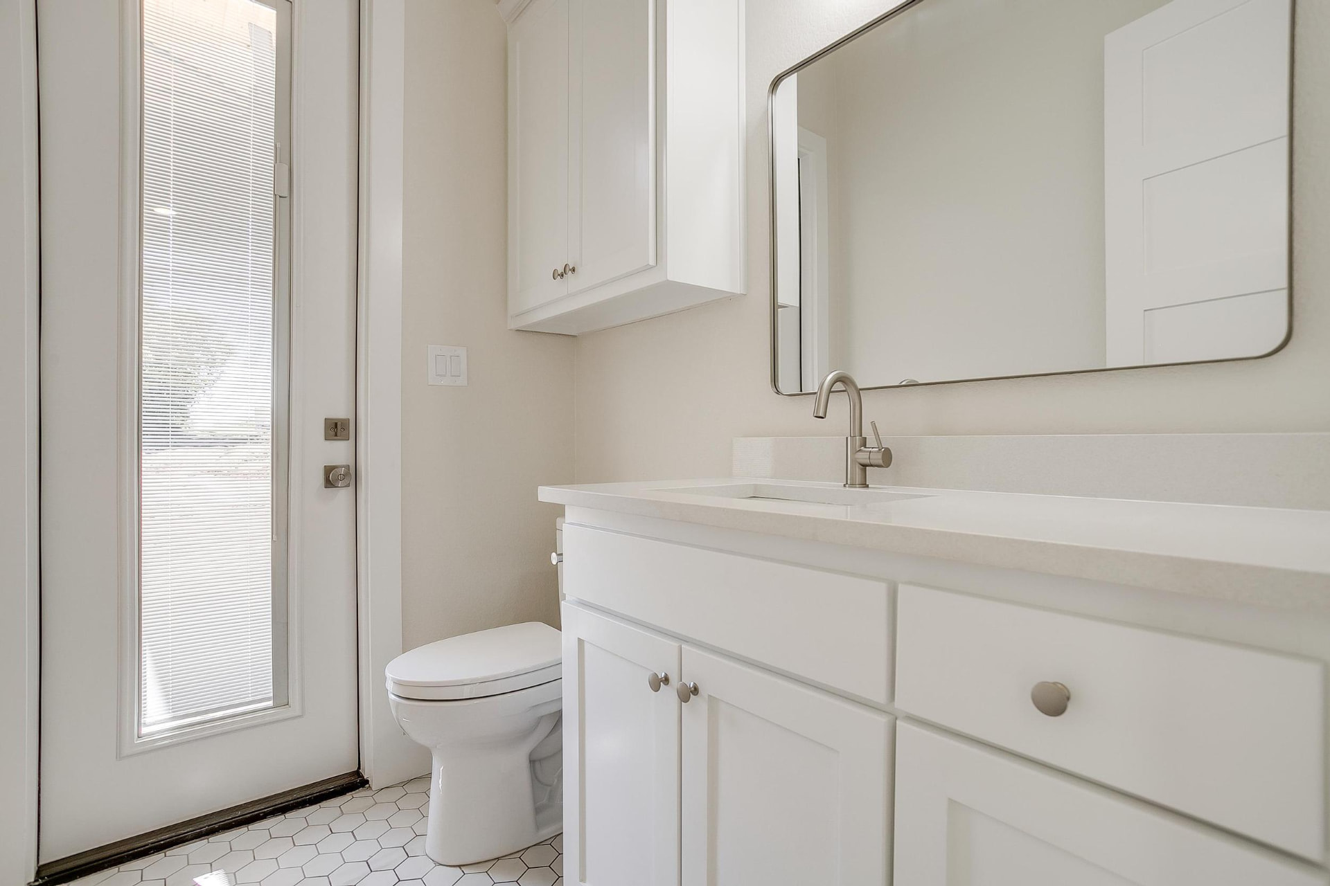 Bath vanity with white cabinets and a gold-framed mirror