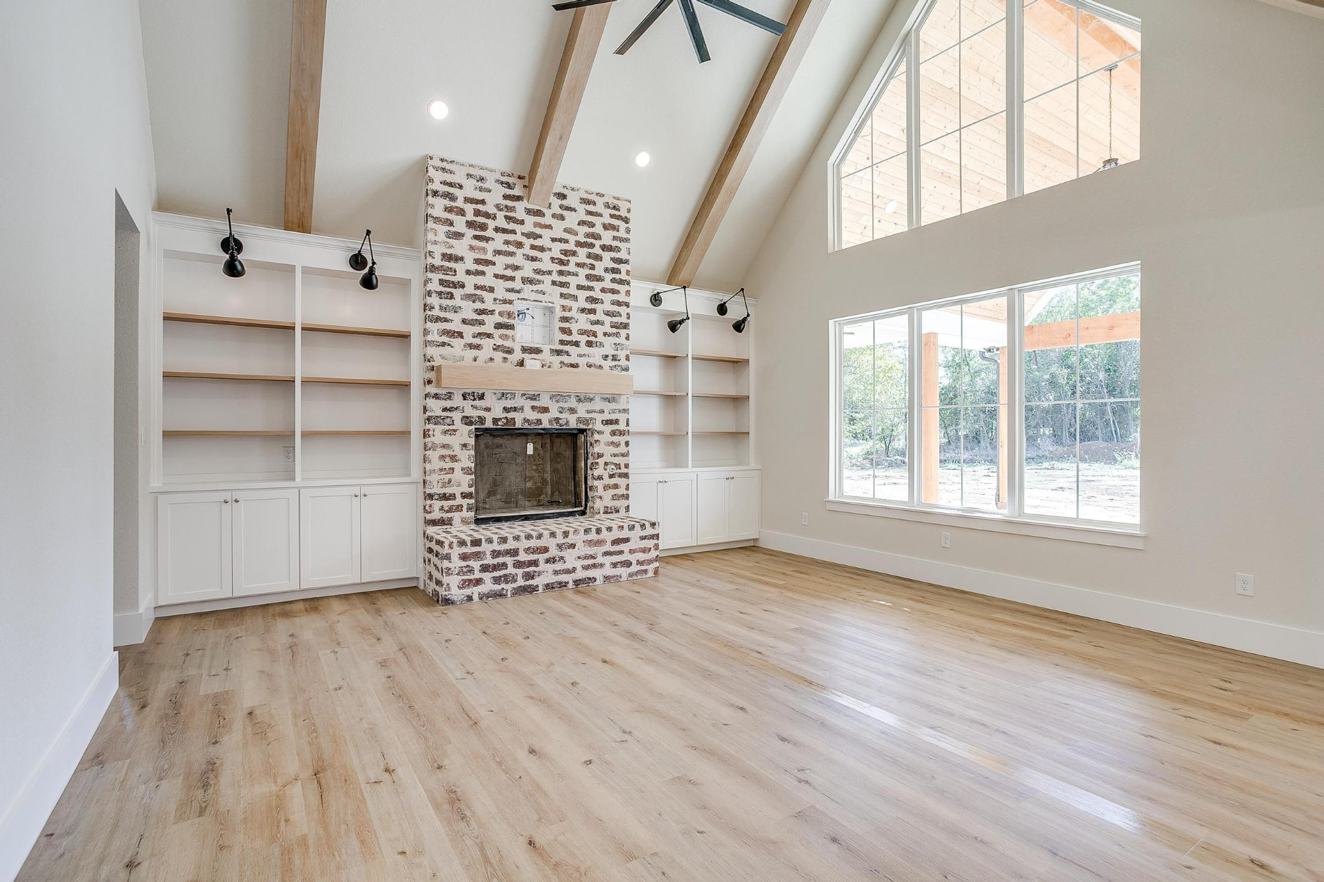 Living room with vaulted ceilings, exposed beams, and a white brick fireplace