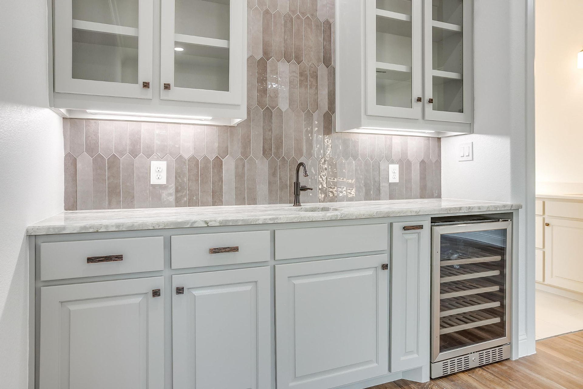 Wet bar with gray cabinetry and picket tile backsplash