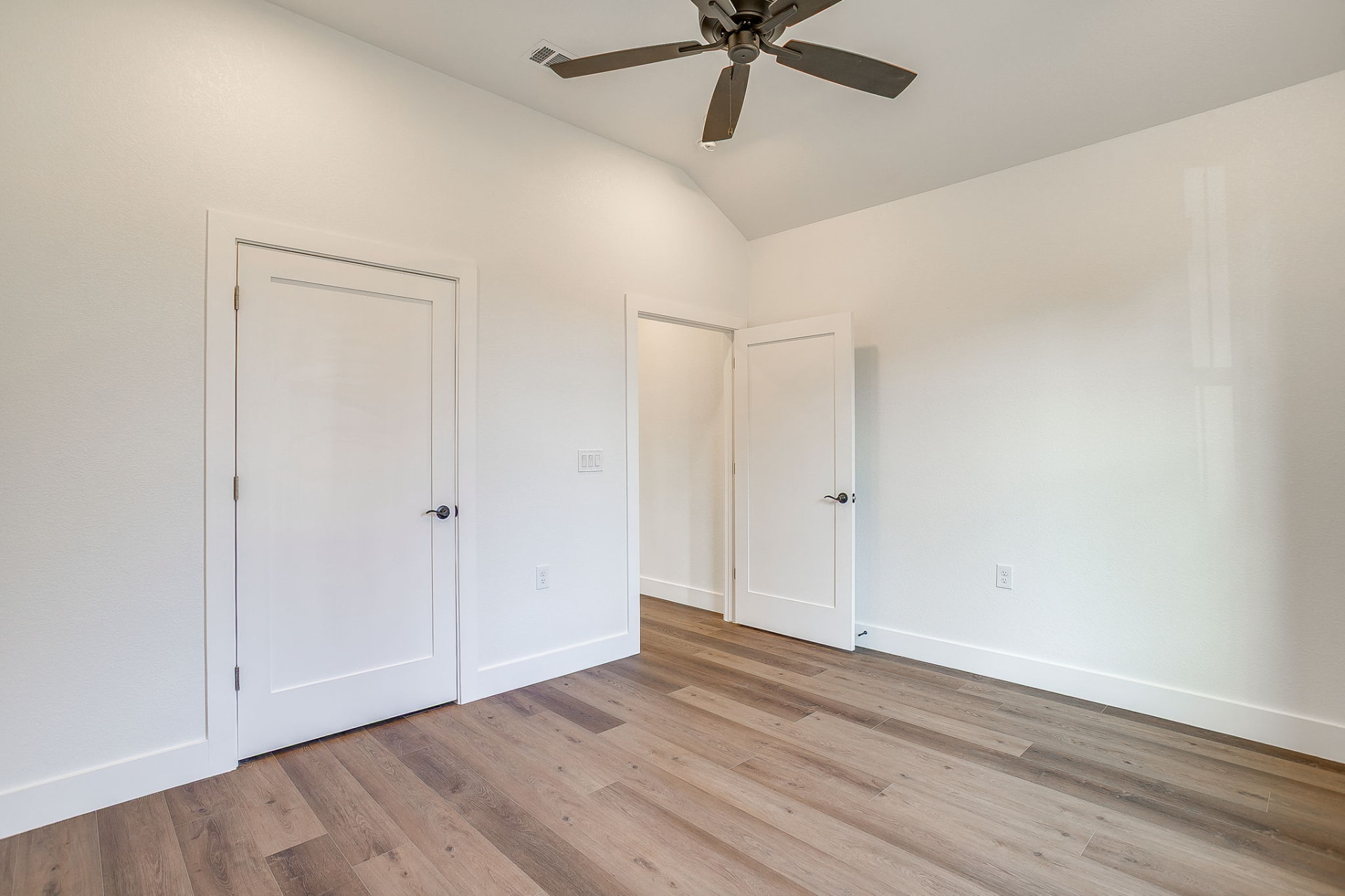 Bedroom with vaulted ceiling, ceiling fan, and dual closet doors